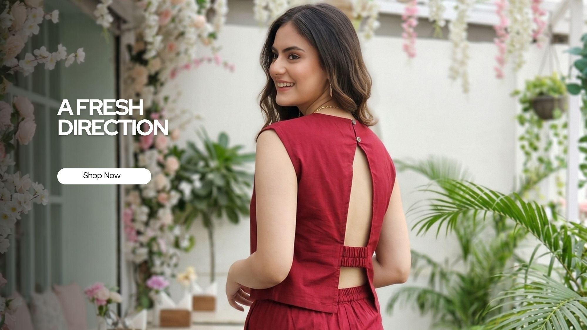 Woman in a Guilt & Class red Co-ord set with an open back standing in a decorated outdoor setting.