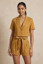 Woman wearing a mustard yellow romper against a beige background