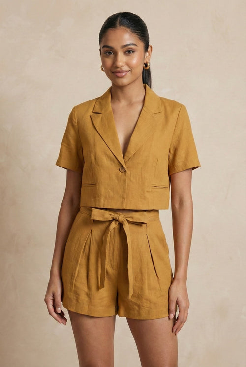 Woman wearing a mustard yellow romper against a beige background