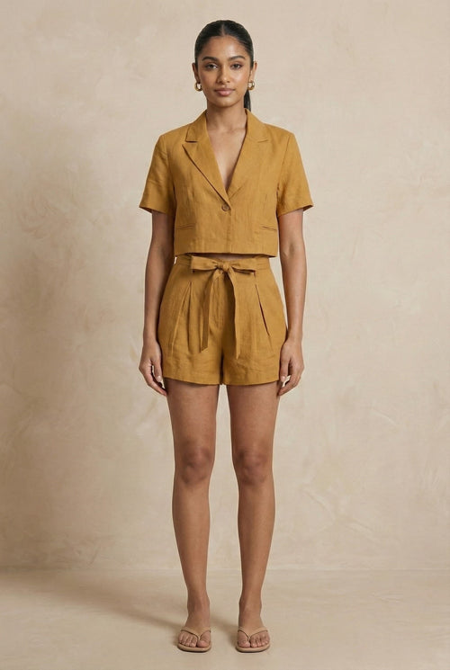 Woman wearing a mustard yellow romper against a beige background