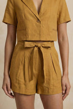 Mustard yellow shorts and top set on a beige background