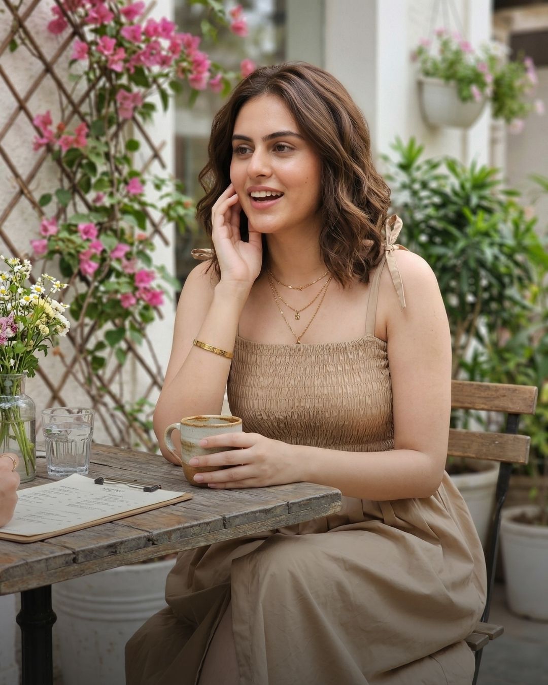 Woman sitting at a table outdoors wearing a Guilt & Class smocked midi dress