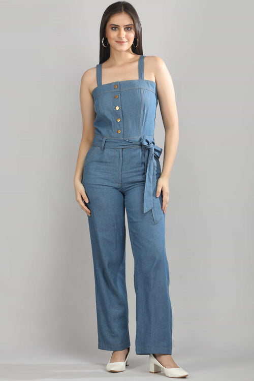 A model wearing the Caught in Denim jumpsuit by Guilt & Class, featuring a panelled bodice, tie-up waist, and wide-leg silhouette in lightweight cotton denim.