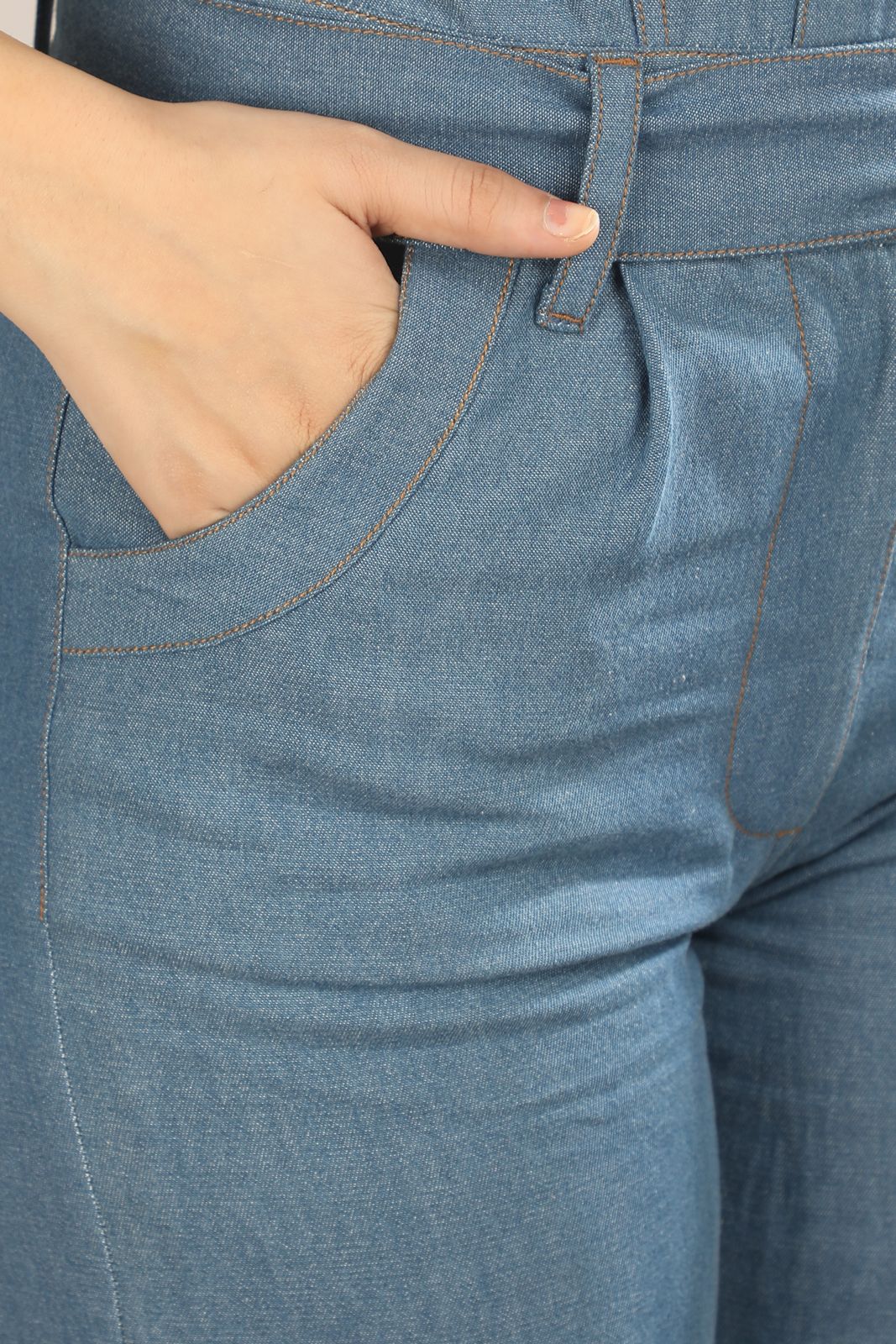 [blue] Close-up of the Caught in Denim jumpsuit by Guilt & Class, featuring functional pockets and lightweight denim construction.