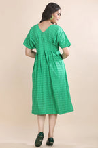 Back view of the green eyelet midi dress, showing the seamless closure, tailored waist, and beautiful draped fit.