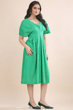 Three-quarter view of the elegant green schiffli dress highlighting the structured bodice and naturally flowing midi-length skirt.