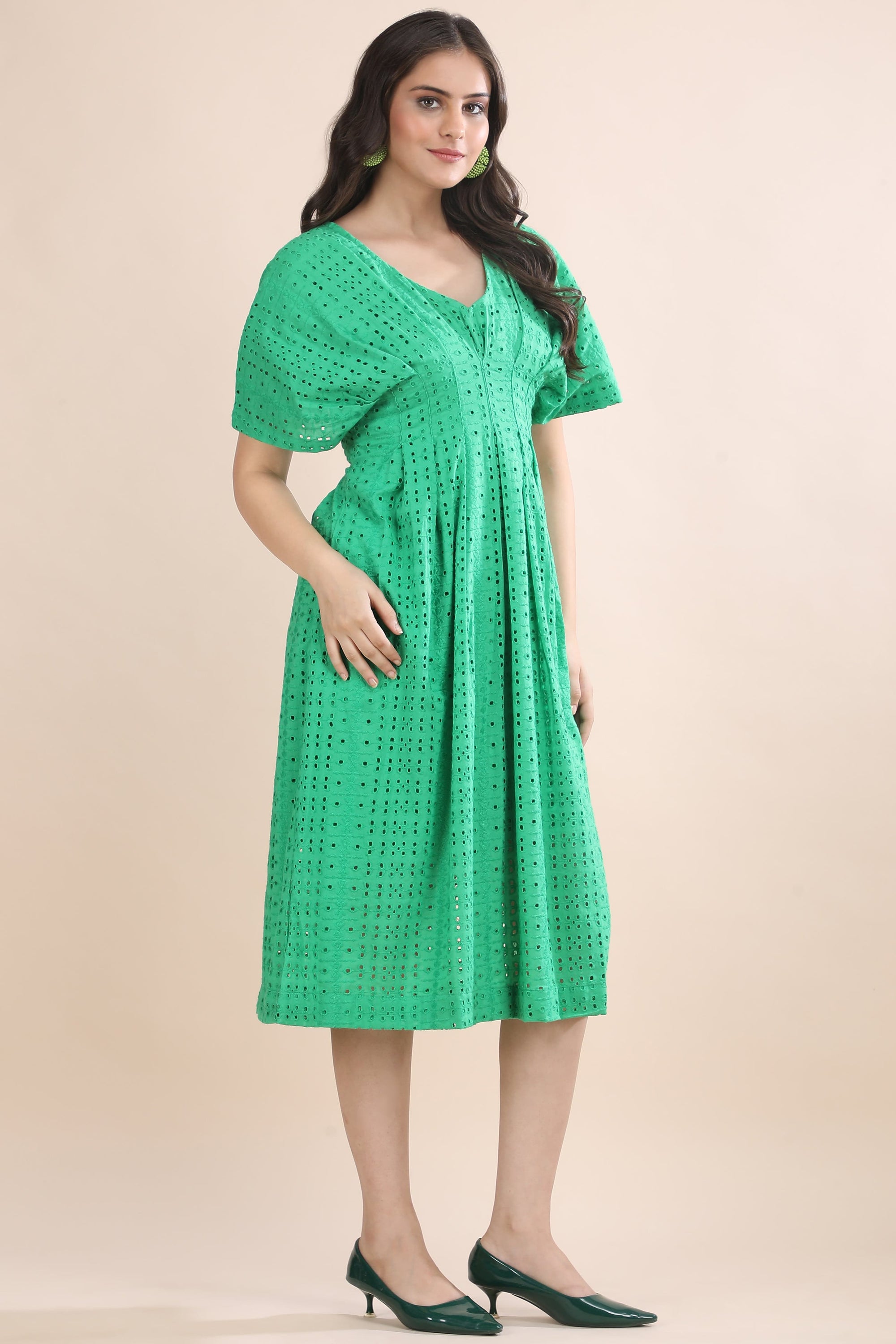 Three-quarter view of the elegant green schiffli dress highlighting the structured bodice and naturally flowing midi-length skirt.