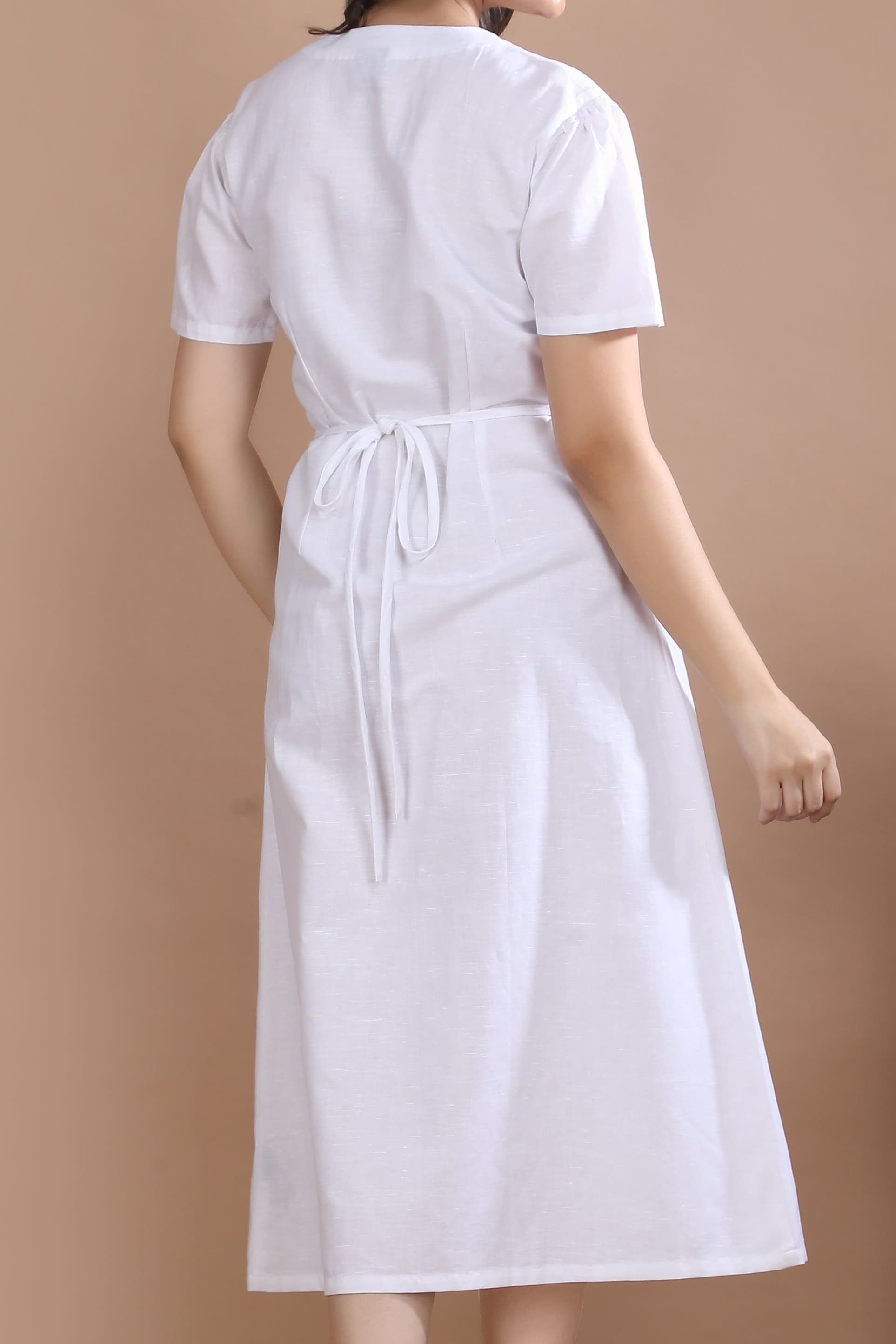 A model in motion wearing the Ivory Wrap Midi Dress by Guilt & Class, highlighting the fluid movement and lightweight cotton-linen fabric.