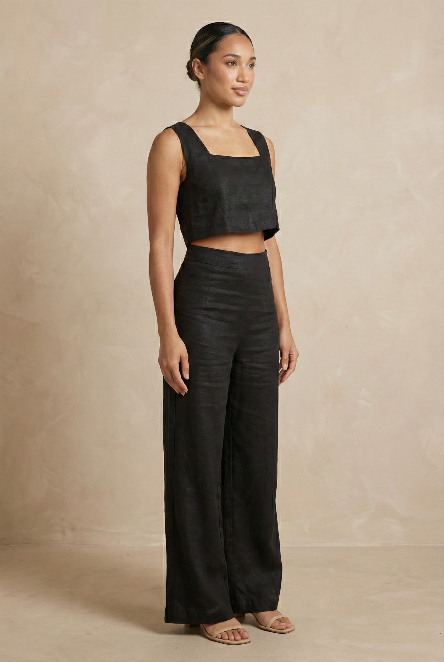 Angled view of the Noir linen co-ord set by Guilt & Class, highlighting the structured silhouette and fluid wide-leg trousers.
