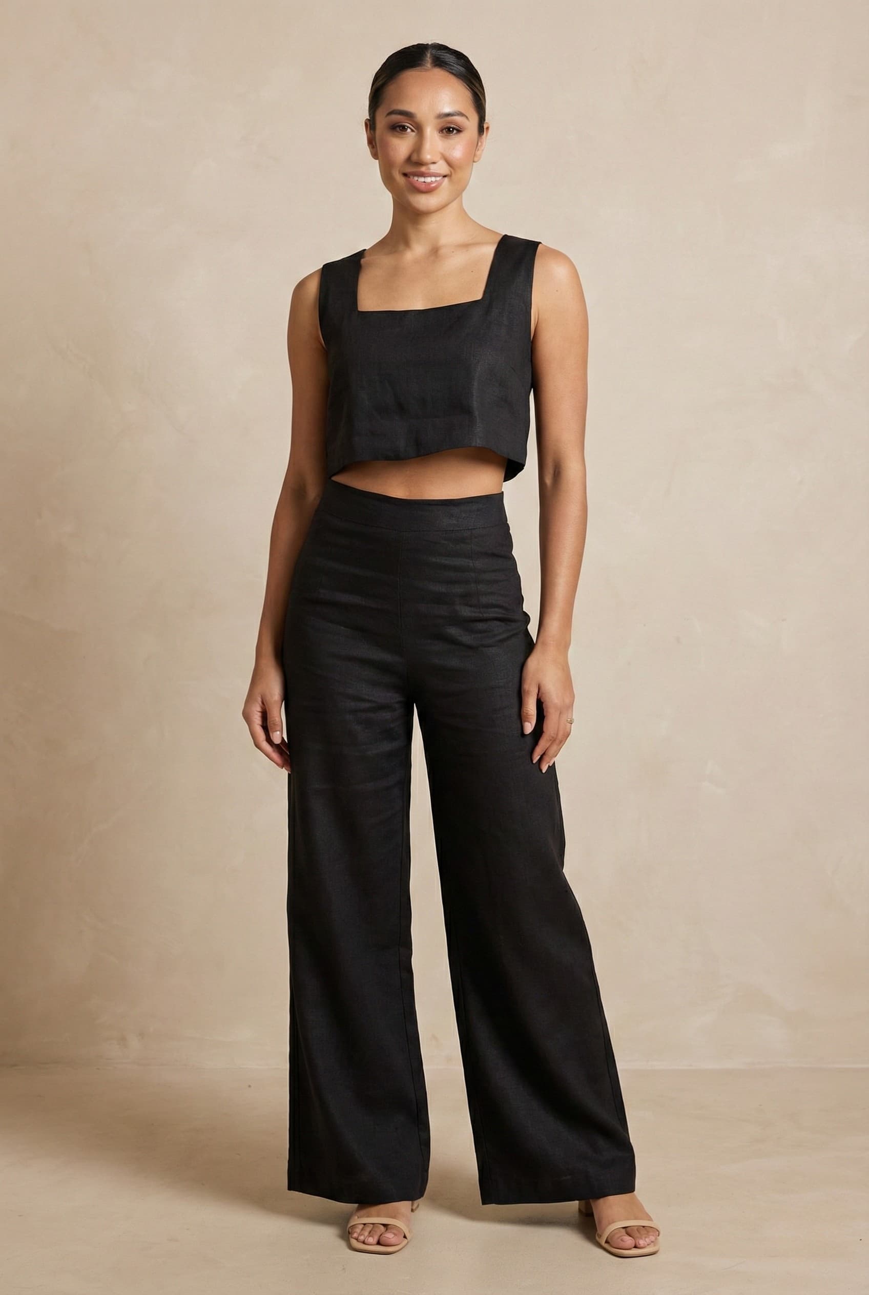A model wearing the Noir linen co-ord set by Guilt & Class, featuring a square-neck crop top and wide-leg trousers in a breathable cotton-linen blend.