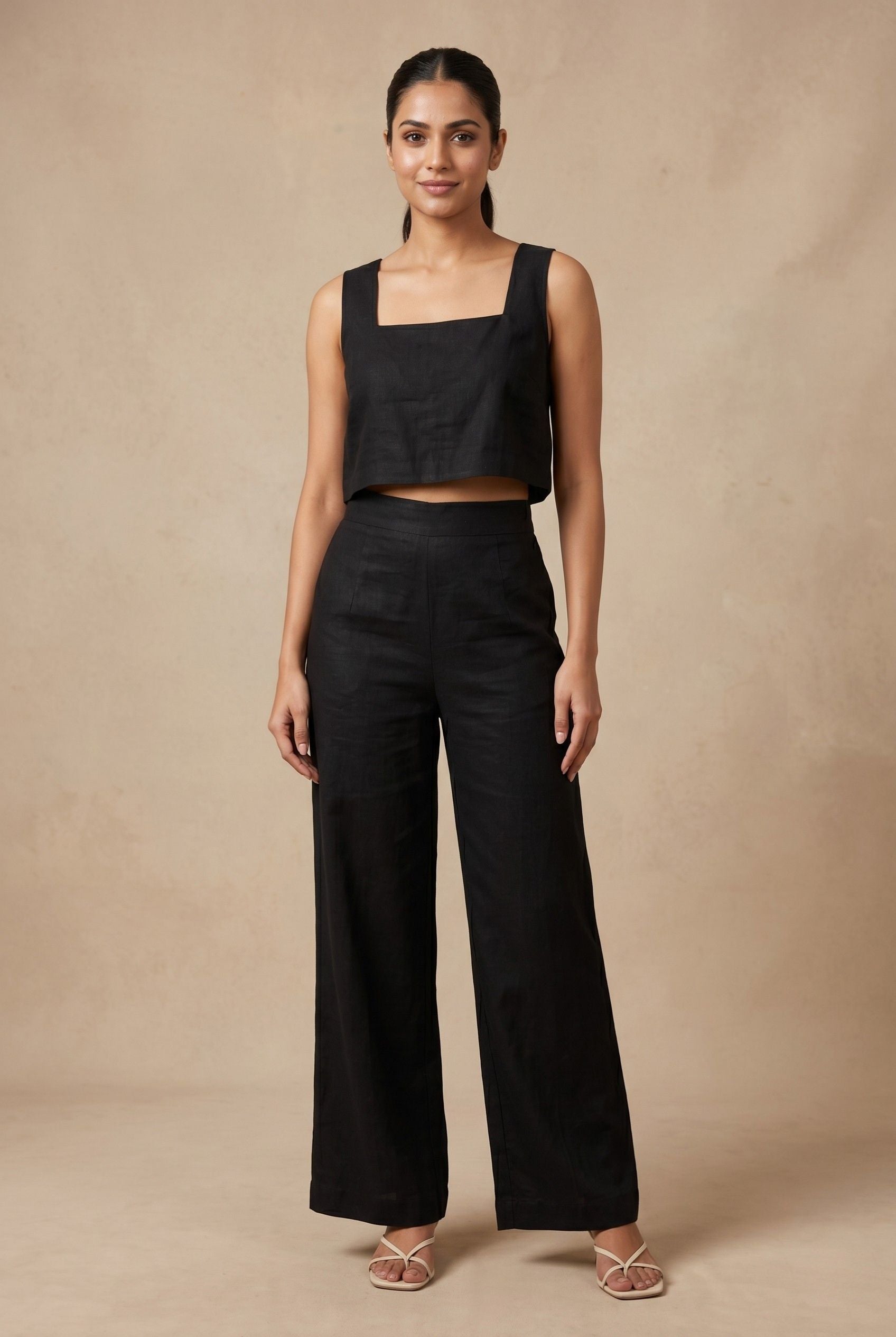A model wearing the Noir linen co-ord set by Guilt & Class, featuring a square-neck crop top and wide-leg trousers in a breathable cotton-linen blend.