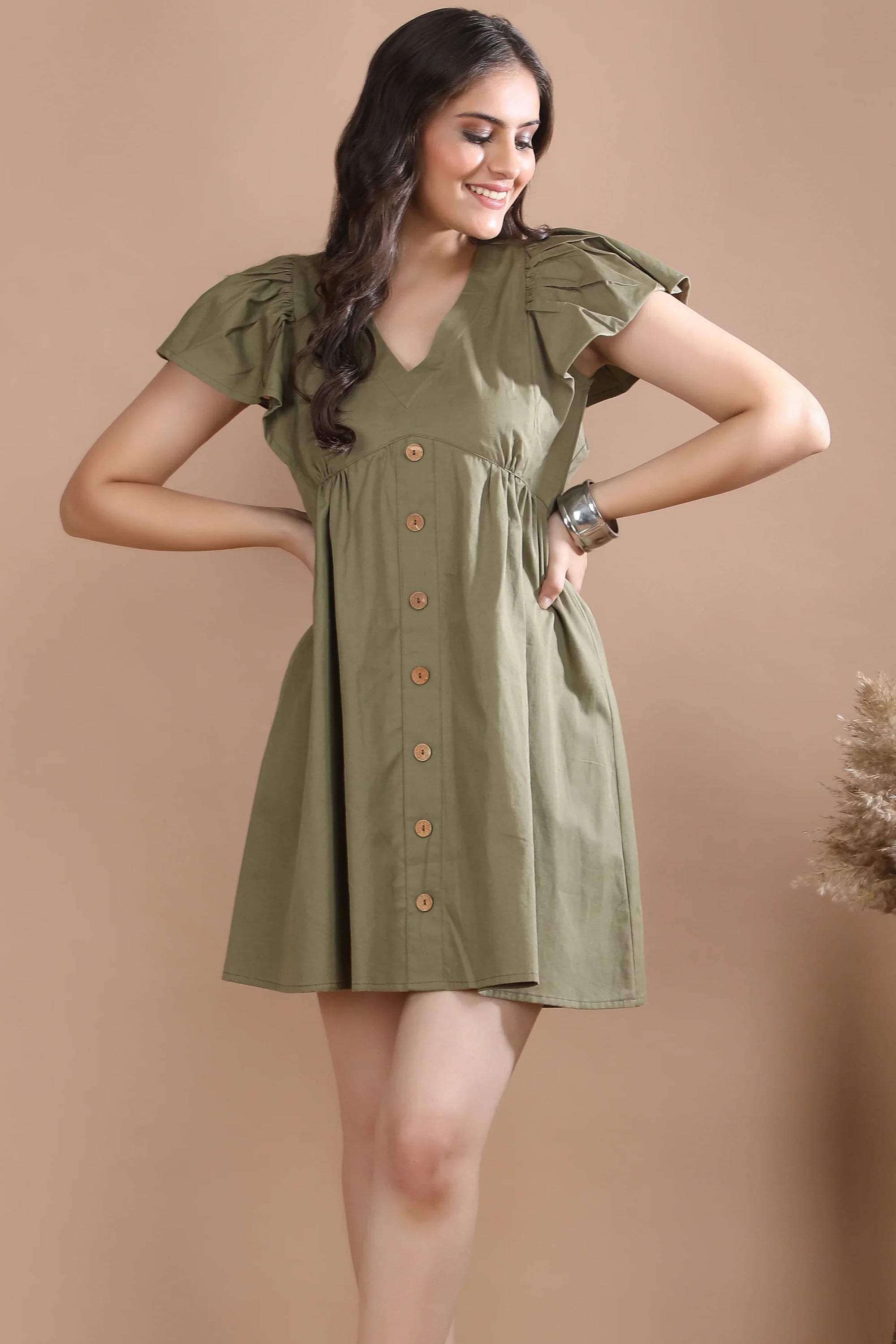 Full-length shot of a woman confidently posing in the premium olive green flutter sleeve westernwear dress by Guilt & Class.