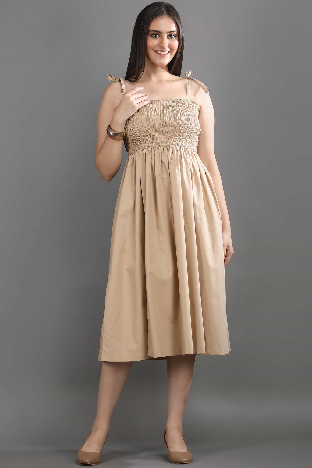 A model wearing the Second Skin midi dress by Guilt & Class, featuring a smocked bodice, adjustable straps, and a soft structured cotton finish.